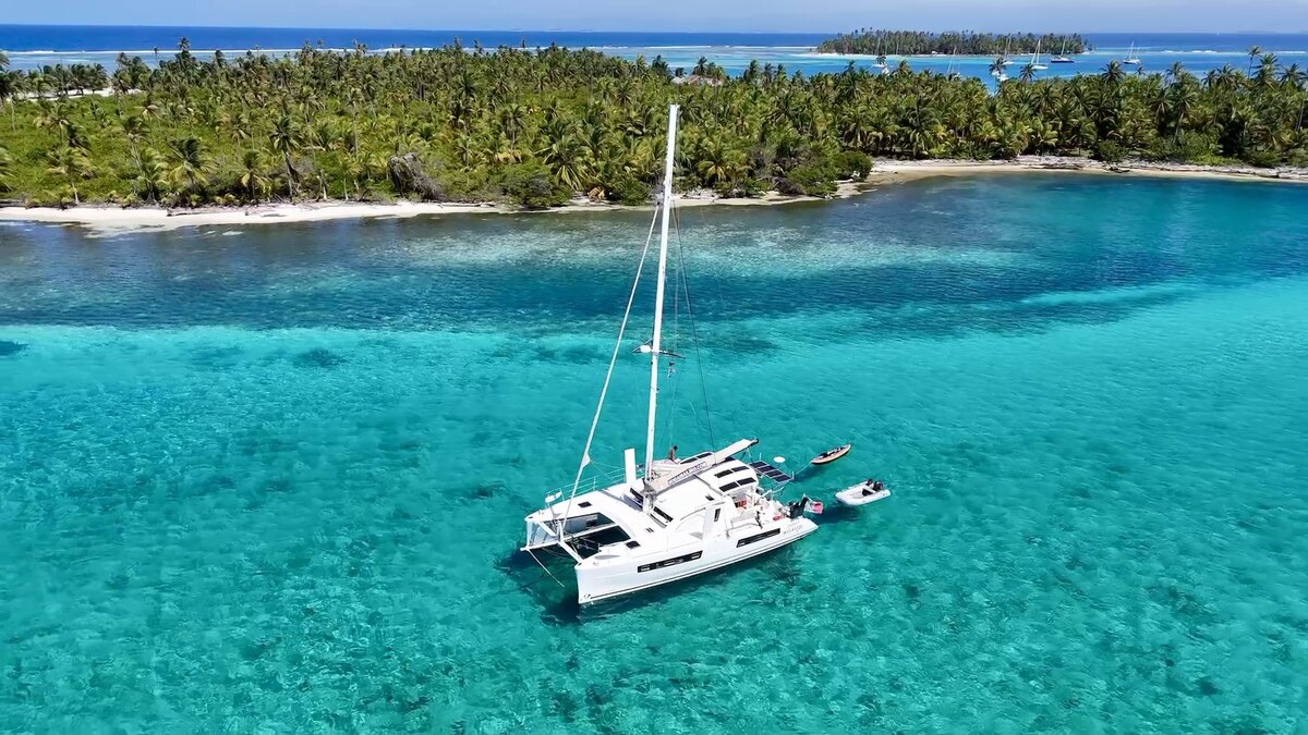 Catamaran Ikigai anchored off a green San Blas island