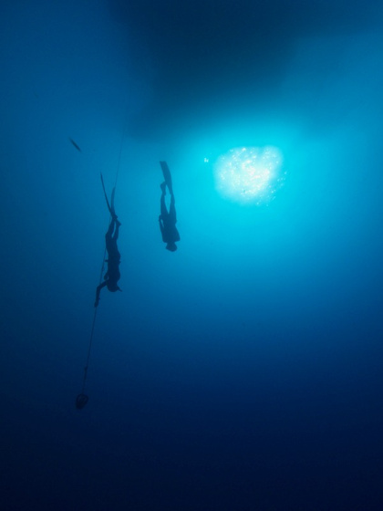 Freedivers on a line in deep blue water